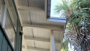 A wooden staircase leading to a covered porch with a white railing, surrounded by palm trees and a view of the sky. - THE PERCH-Beach Cottage- FREE GOLF CART-Just Minutes from the Gulf/BEACH! (Panama City Beach)