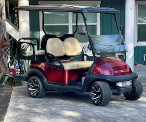 Une voiturette de golf est garée devant un bâtiment dont la porte de garage est visible.