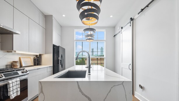 A modern kitchen with a central island, stainless steel appliances, and a large window providing a view of the city.