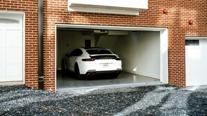 A white sports car parked inside a garage attached to a brick building.