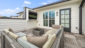 An outdoor patio with a sectional sofa, a coffee table, and a large window.