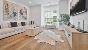 A modern living room with a wooden floor, a white sofa, a coffee table, and artwork on the walls.