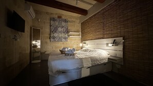 A modern bedroom with a large bed, bedside tables, a wall-mounted TV, and a decorative wall piece. - Heritage Living Apartment With Spectacular Views (Zebbug)