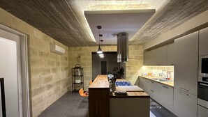 A modern kitchen with a central island, built-in appliances, and a stone wall backsplash. - Heritage Living Apartment With Spectacular Views (Zebbug)