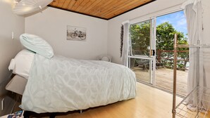 Een slaapkamer met een bed, een houten plafond, een raam met gordijnen en een fietskunstwerk aan de muur.
