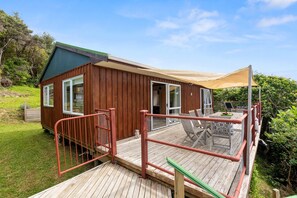 Une cabane en bois dotée d’une terrasse, d’un patio couvert et d’un espace extérieur clôturé.