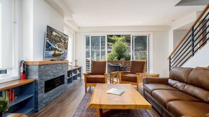 A modern living room with a fireplace, a television, a sofa, and a dining area with chairs.