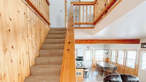 A wooden staircase leading to a second floor with a dining area and a leather sofa. - Stunning lake house with private dock (Joseph)