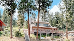 A wooden deck leading to a swimming area with clear water, surrounded by trees and a house with a deck. - Stunning lake house with private dock (Joseph)