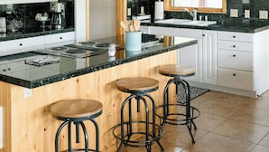 A modern kitchen with a central island, bar stools, white cabinetry, and a window providing natural light. - Stunning lake house with private dock (Joseph)
