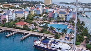 Puerto deportivo con edificios de colores, piscina y un yate amarrado.