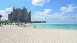 Una playa con un gran hotel al fondo.