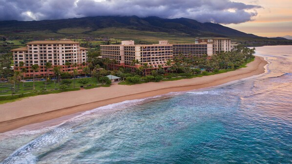 Hotel na praia com vários edifícios, areal dourado e vista para o oceano.