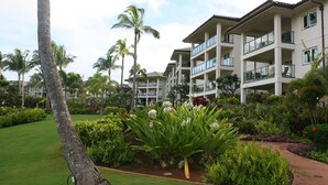 A multi-story hotel with balconies, surrounded by lush greenery and palm trees.