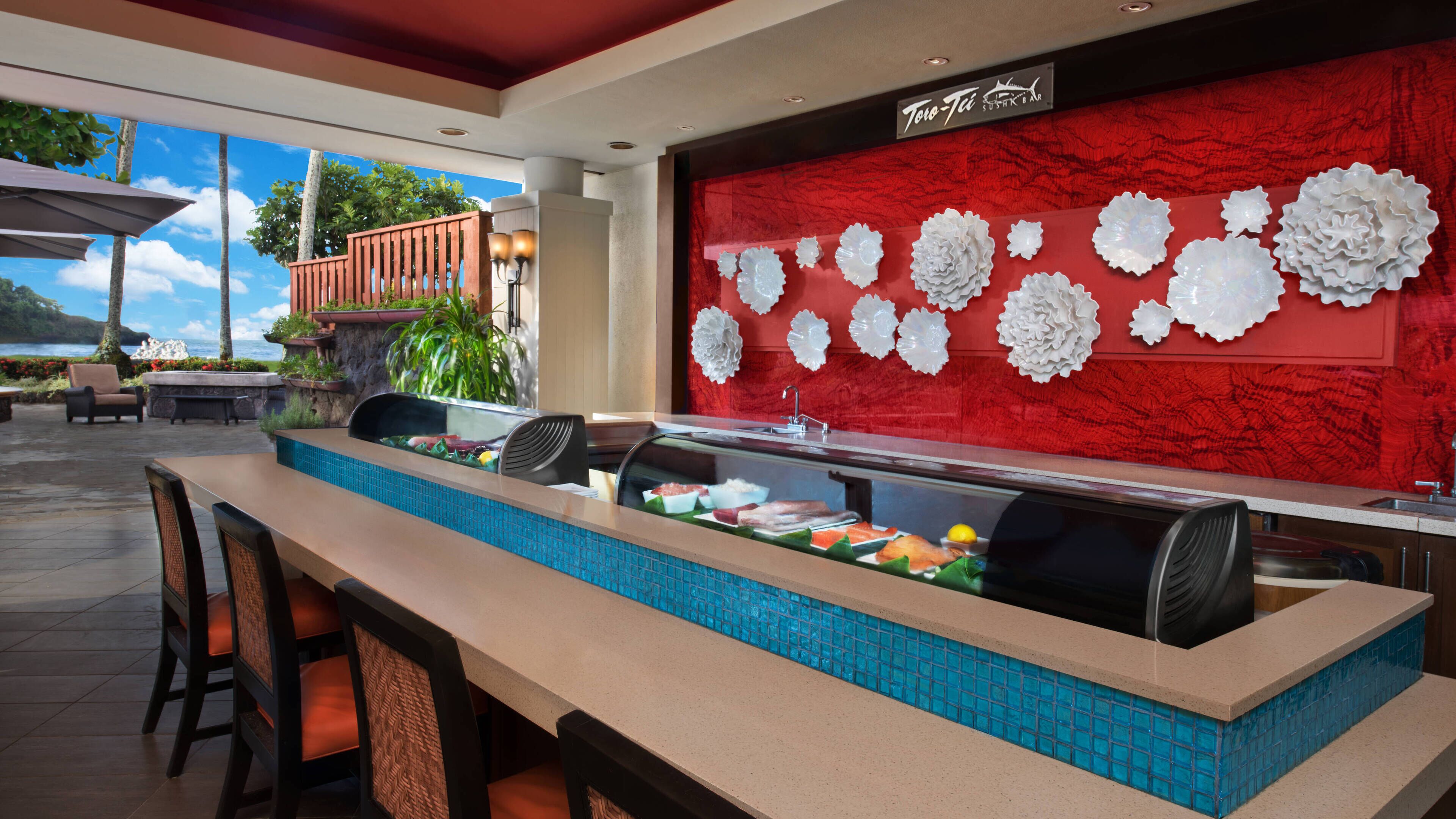 A sushi bar with a red wall and white decorative plates.