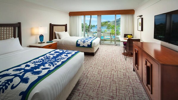 A hotel room with two beds, a desk, a TV, and a balcony with a pool view.