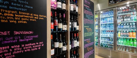 A wine and beverage display area with various bottles and a refrigerator.