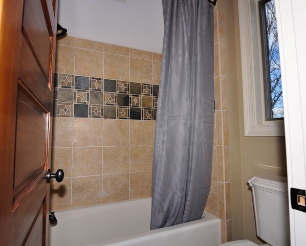 A bathroom with a bathtub, a shower curtain, and a toilet.