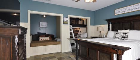 A bedroom with a bed, a wooden dresser, a ceiling fan, and a wall with a sign.