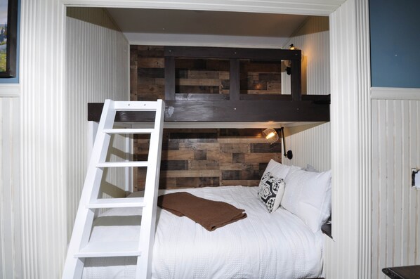 A bunk bed with a ladder, a wooden headboard, and a bedside lamp.