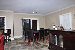 A dining area with a table and chairs, a bar counter, and a door leading to another room.