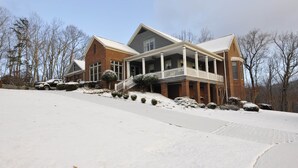 A large house with a covered porch, a brick exterior, and a snow-covered driveway. - Unwine'd With a View (Hayesville)
