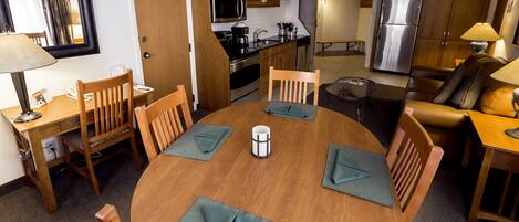 A compact hotel room with a dining area, kitchenette, and a living space.