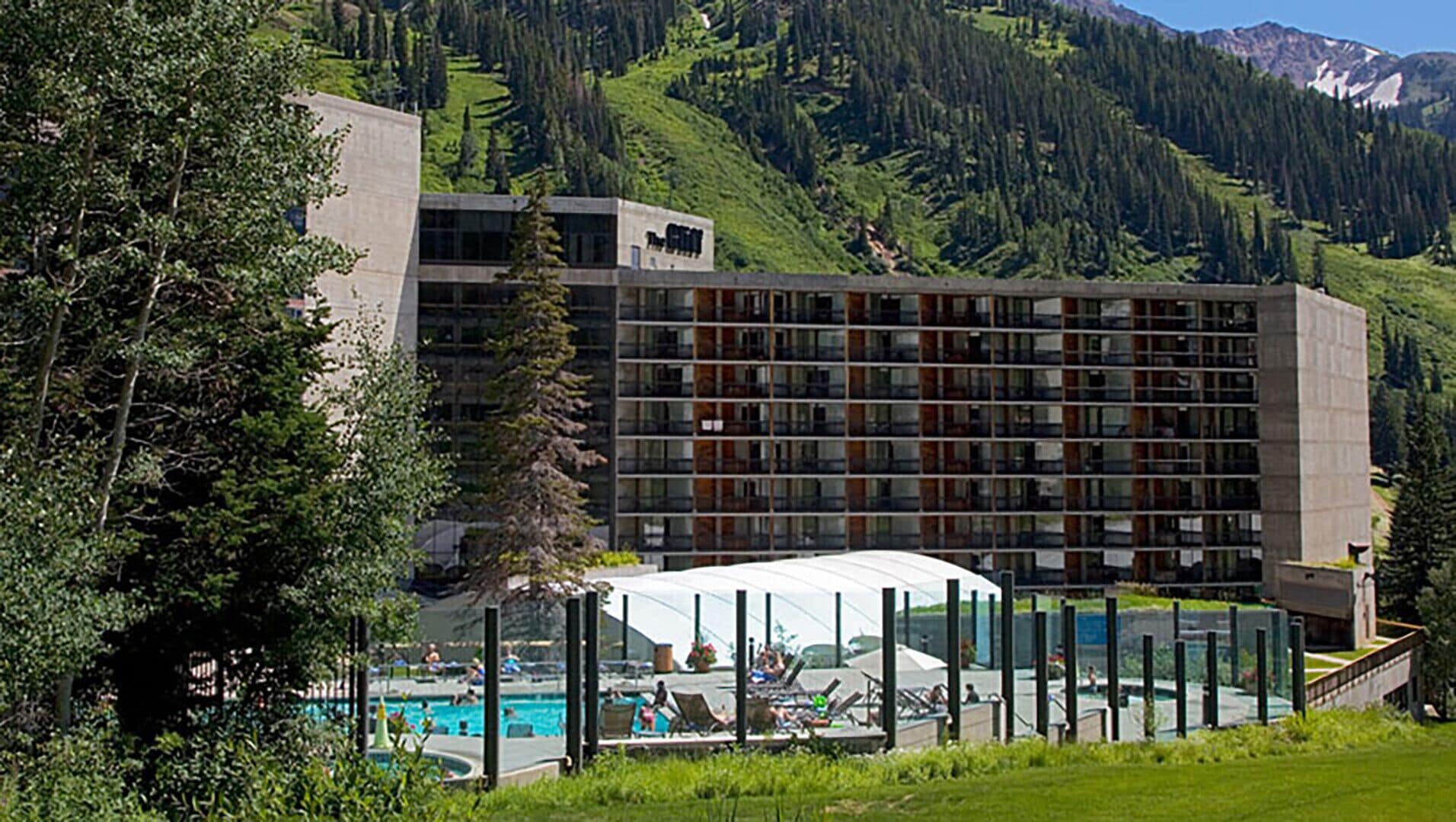 Un hôtel doté d’une piscine, entouré de verdure et de montagnes.