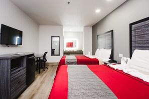 A hotel room with two beds, a desk, a TV, and a mirror. - Palace Inn Baytown Spur TX-330 (Baytown)