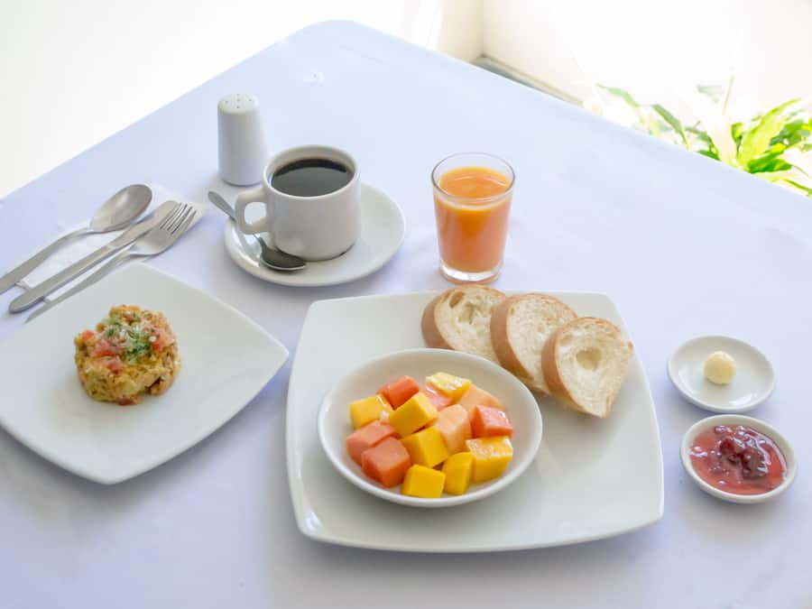 A breakfast setting with a plate of scrambled eggs, toast, and fruit, a cup of coffee, and a glass of orange juice.