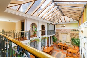 Un intérieur à plusieurs niveaux doté d’un plafond en verre, de planchers en bois et d’un escalier avec une rampe dorée.