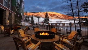 A fire pit with chairs around it, overlooking a snowy landscape with trees and a building in the background. - 2 Bedroom - Marriott's MountainSide at Park City - Full Resort Access (Park City)