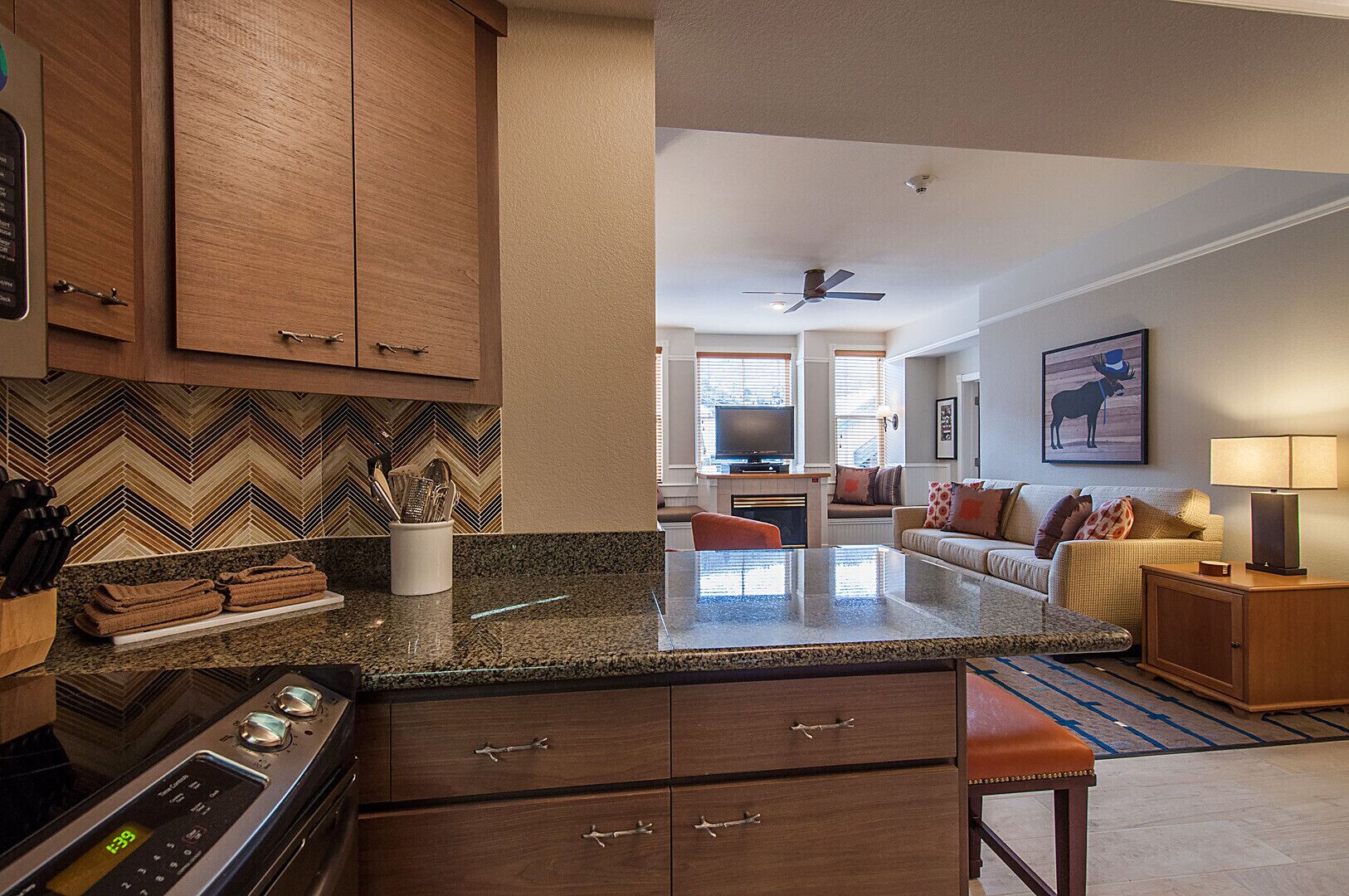 A modern kitchen with granite countertops, wooden cabinets, and a built-in stove.
