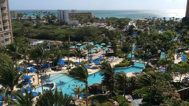 A resort with multiple swimming pools, palm trees, and a view of the ocean.