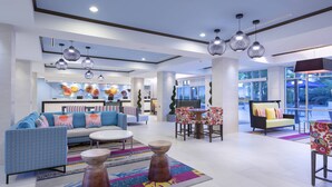 Een moderne hotellobby met een bank, stoelen, een zithoek en een receptiebalie.