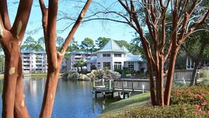 A lakeside view of a resort with a gazebo, a dock, and a building with a blue roof.