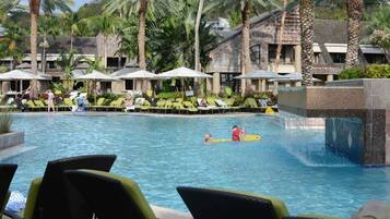 Relax by the pool with lounge chairs and umbrellas, surrounded by a modern design and a soothing waterfall feature.