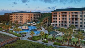 Un complejo turístico con varias edificaciones, una piscina central y vegetación circundante.