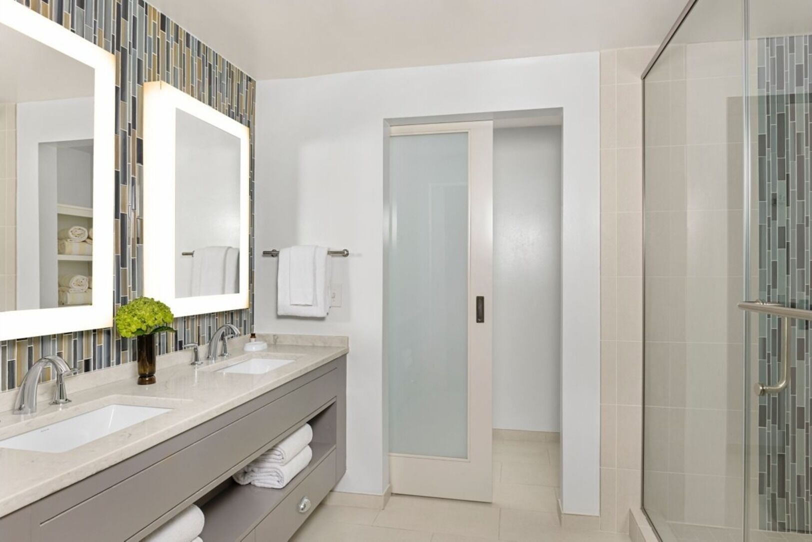 Uma casa de banho moderna com duas pias, um espelho grande e zona de duche.