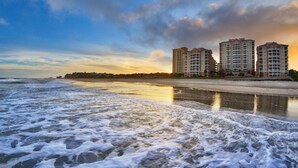A beachfront hotel with multiple high-rise buildings, a sandy beach, and ocean waves.