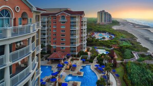 A hotel with multiple floors, a pool area, and a view of the beach. - Oceanfront - 2 Bedroom - Marriott's OceanWatch Villas at Grande Dunes - Full Resort Access (Myrtle Beach)