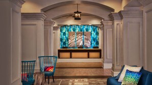 A lobby with a wooden bench, two blue chairs, a blue sofa, and a ceiling fan. - Oceanfront - 2 Bedroom - Marriott's OceanWatch Villas at Grande Dunes - Full Resort Access (Myrtle Beach)