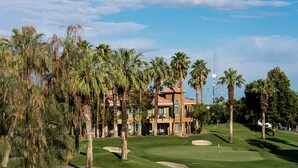 Un parcours de golf doté d’un club-house et bordé de palmiers.