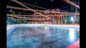 Una pista de hielo con luces colgantes y un edificio al fondo.