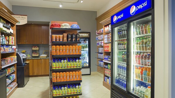 Un supermercado con un mostrador refrigerado de Pepsi y una estantería llena de bebidas deportivas y productos de cuidado personal.
