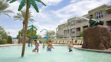 Relax by the pool surrounded by palm trees and a large rock formation.