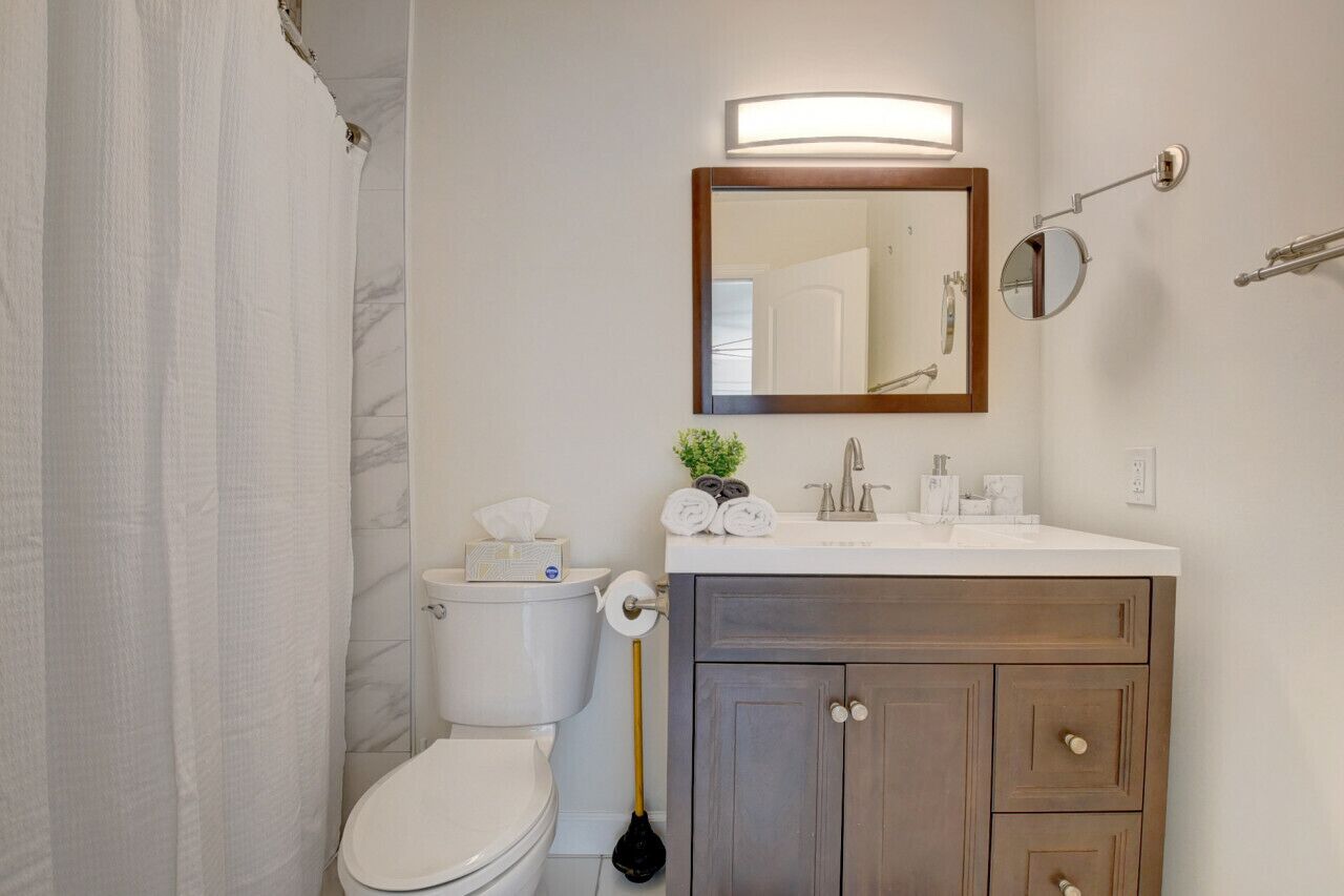 Ein Badezimmer mit Toilette, Waschbecken und Spiegel sowie einer Duschkabine.