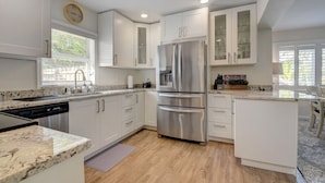 A modern kitchen with white cabinets, stainless steel appliances, and a marble countertop. - Bliss Near Beach w/ Guest House + Salt Heated Pool (Boynton Beach)