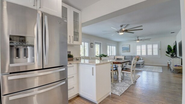 A modern kitchen with stainless steel appliances, a dining area with a table and chairs, and a ceiling fan. - Bliss Near Beach w/ Guest House + Salt Heated Pool (Boynton Beach)
