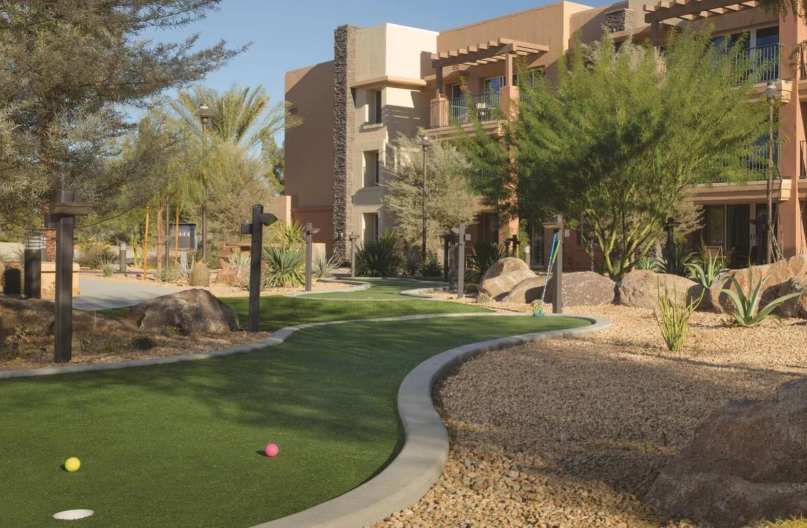 Un parcours de golf doté d’un green d’entraînement, entouré d’un espace paysager agrémenté de rochers et d’arbres.